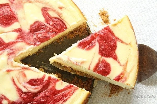 Creamy strawberry swirl cheesecake topped with fresh strawberries and a swirl of strawberry puree.