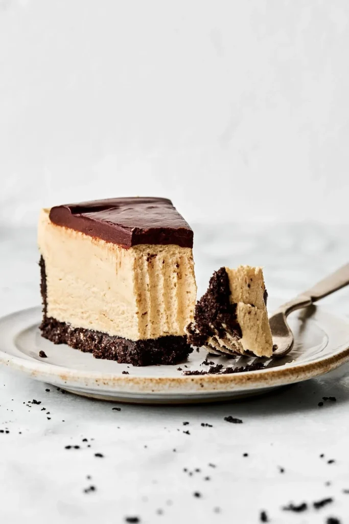 Delicious creamy peanut butter cheesecake topped with chocolate drizzle and peanuts