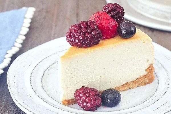 Creamy vegan New York cheesecake topped with fresh fruit and mint leaves.