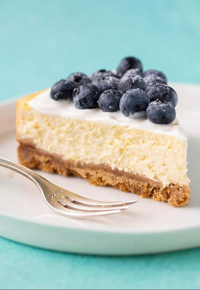 Lemon Cheesecake: Creamy Zesty Delight 4 Creamy lemon cheesecake topped with fresh lemon zest on a white plate