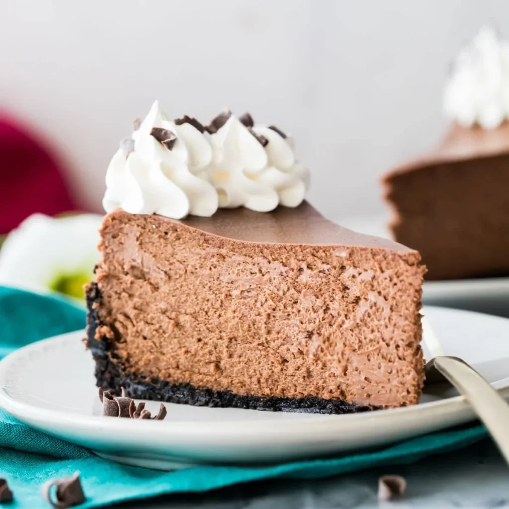 Slice of ultimate decadent chocolate cheesecake topped with fresh chocolate shavings